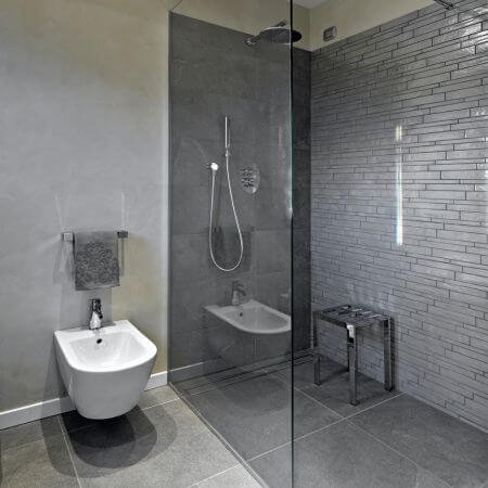 Modern bathroom with tiles, glass shower door, and sleek fixtures. Tub To Shower Conversion