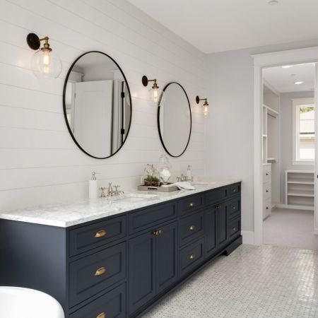 A sleek bathroom featuring a glass-enclosed shower, a freestanding bathtub, and a double sink vanity. The walls are adorned with mosaic tiles.