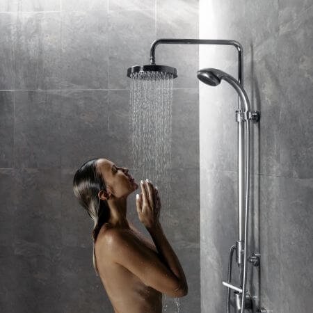 A woman showering with arms raised.