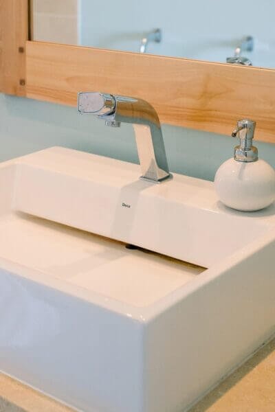 A white faucet and mirror above a bathroom sink.