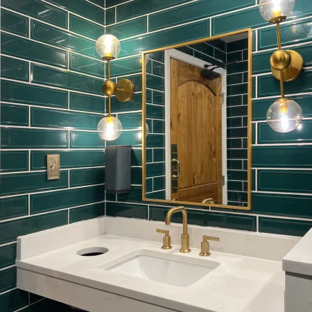 green-tile-bathroom-vanity-and-mirror A modern bathroom vanity with green tiled walls and gold fixtures.